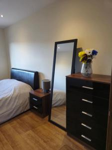 a bedroom with a dresser with a mirror and a bed at Self-catering extended family home in Edinburgh