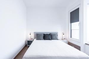 a white bedroom with a large bed and two windows at Novi Sad's Quiet Quarters in Novi Sad