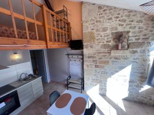 a kitchen with a table and a stone wall at Gîtes de la chocolaterie in Vire-sur-Lot