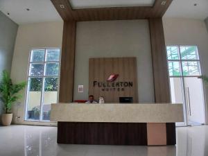 a man sitting at a reception desk in a lobby at Fullerton suites C homestay in Silang