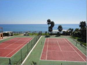 a tennis court with the ocean in the background at Alhamar Cabopino Living Apartment in Málaga