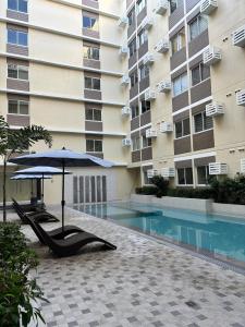 a swimming pool with an umbrella and chairs and a building at Fullerton suites C homestay in Silang +7 photos