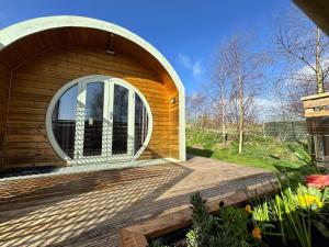 a circular building with a round window on a wooden deck at Grange Beck Farm Glamping in Kildwick