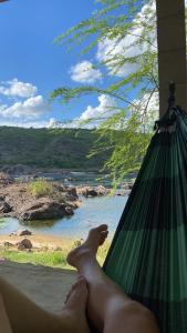 a person laying in a hammock looking out at the water at Chalé Velho Chico in Canindé de São Francisco +21 photos