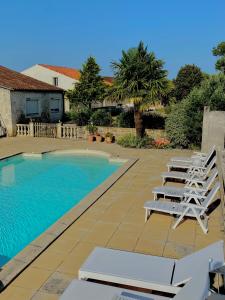 a swimming pool with lounge chairs next to a house at Les gîtes des Lauriers roses Chambre privée Île d Aix in Geay