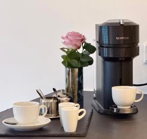 eine Kaffeemaschine mit zwei Tassen und eine Rose in einer Vase in der Unterkunft Teuto Loft in Hörstel