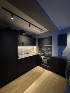 a kitchen with black cabinets and a wooden floor at 3-room downtown apartment in Trondheim +3 photos