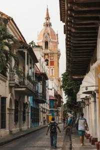 a man walking down a street with a clock tower at Tranquila y cerca de la magia in Cartagena de Indias +28 photos