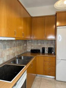 a kitchen with wooden cabinets and a sink at Halkidiki Kallithea Family House across the beach in Kallithea Halkidikis