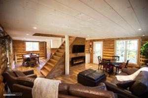 a living room with a staircase in a log house at Chalet Le Merlot in Mandeville