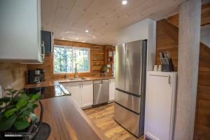 a kitchen with a stainless steel refrigerator and wooden walls at Chalet Le Merlot in Mandeville