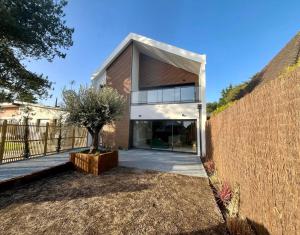 a house with a tree in front of a fence at Villa Stella-plage proche Le Touquet pour 8 personnes in Cucq