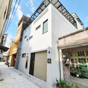 un edificio blanco con garaje en una calle en Maru Yang 馬路楊宿屋, en Tainan