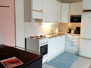 a kitchen with white cabinets and a sink and an oven at Taideniityn Maa 1 - 4lle in Varkaus