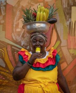 a woman eating a banana with a bowl on her head at Tranquila y cerca de la magia in Cartagena de Indias