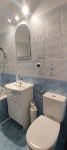 Un baño con un inodoro blanco y un lavabo. en Słoneczna kawalerka, en Gdansk