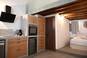 a kitchen with wooden cabinets and a bed in a room at Plakares Studio 1 in Kithnos