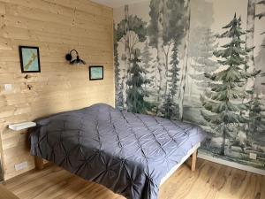 a bedroom with a bed and trees on the wall at Maison Vaniméou in Pouzauges