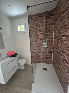 a bathroom with a shower with a brick wall at Maison Vaniméou in Pouzauges