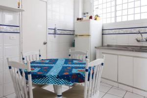 a kitchen with a table and chairs and a kitchen with a refrigerator at Pitangueiras Frente Total Mar pé na areia in Guarujá