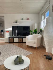 a living room with a large television and a white chair at The Vineyard View in Zell an der Mosel