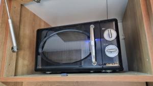 um micro-ondas preto sentado em cima de uma prateleira em Khan Yaelim em Arad