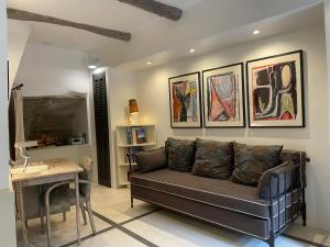 a living room with a couch and paintings on the wall at La Calade, maison de village in Gordes