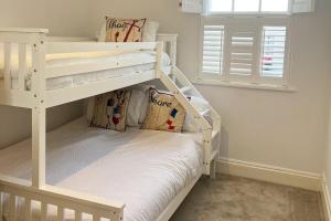 ein weißes Etagenbett in einem Zimmer mit Fenster in der Unterkunft Harbour-side, 2-bed Mews Apartment, in Torquay