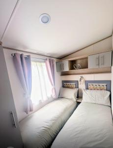 two beds in a small room with a window at Wallows Lodge with private hot tub in St Austell