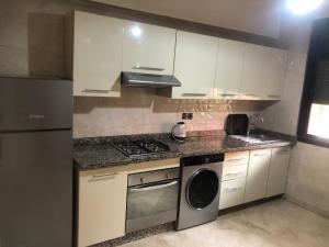 Una cocina con gabinetes blancos, estufa y lavavajillas. en Résidence Babylone Y - Appartement 2 Chambres, en Marrakech