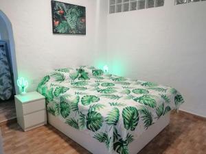 a bedroom with a bed with a green and white comforter at Casamaria in Tarajalejo