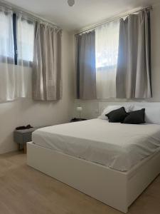 a bedroom with a large white bed with two windows at AL 31 Bg in Bergamo