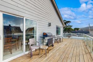 una terrazza con barbecue e sedie su una casa di Seaside Serenity a Seaside