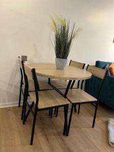 een houten tafel en stoelen met een potplant erop bij Apartment facing Covent Garden station in Londen