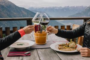 due persone sedute a un tavolo con un bicchiere di vino di Die Acherberg Alm a Oetz