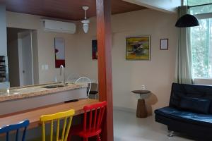 een keuken en een woonkamer met een bar en stoelen bij Condomínio Jardins in Garopaba +280 foto's