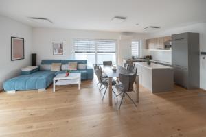 a living room with a blue couch and a kitchen at Amaria Downtown Aparthotel Villach in Villach