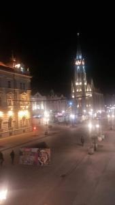 a large building with a clock tower at night at Apartman Biljana in Novi Sad