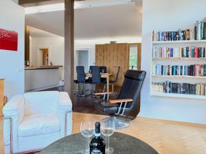 a living room with a white chair and a table with wine glasses at Ferienwohnung Seeperle49 - Besonders, stilvoll mit eigenem Badestrand in Nonnenhorn