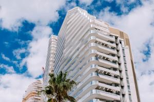 a tall white building with a palm tree at Sunset Cliffs - Vida de Luxury in Benidorm