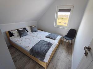 a bedroom with a bed with a window and a chair at Domek letniskowy nad morzem in Osieki Leborskie