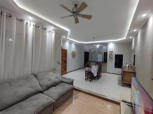 a living room with a couch and a ceiling fan at Casa com garagem, ar condicionado, sala tv e jantar, cozinha completa e lavanderia in Taubaté