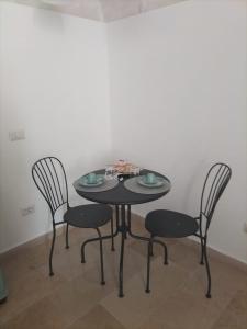 a black table with four chairs in a room at La suite del Marchese a Vieste in Vieste