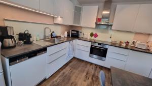 a kitchen with white cabinets and a wooden floor at Moderne Wohnung Cathy in Bad Iburg +16 photos
