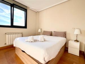 a bedroom with a large white bed with two towels at Apartamento Olmeca - Monabri in Santander +12 photos