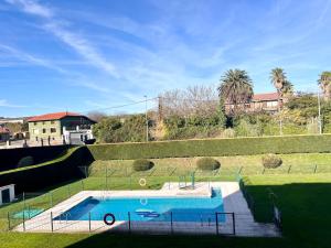 a swimming pool in a grassy field with a house at Apartamento Olmeca - Monabri in Santander