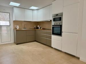 a large kitchen with white cabinets and appliances at Bungalow Timple 2 in Puerto del Carmen