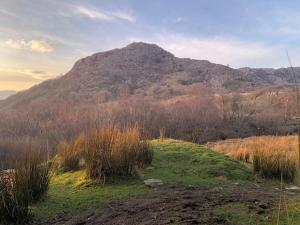 a hill with a mountain in the distance with a field at Cottage Retreat Snowdonia in Capel-Curig +9 photos