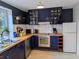 a kitchen with blue cabinets and a white refrigerator at Fjord View Cabin Near Bergen & Nature in Grottveit