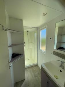a white bathroom with a shower and a sink at Low Budget - Luxe 4 persoons chalet met TV aan het Lauwersmeer in Lauwersoog